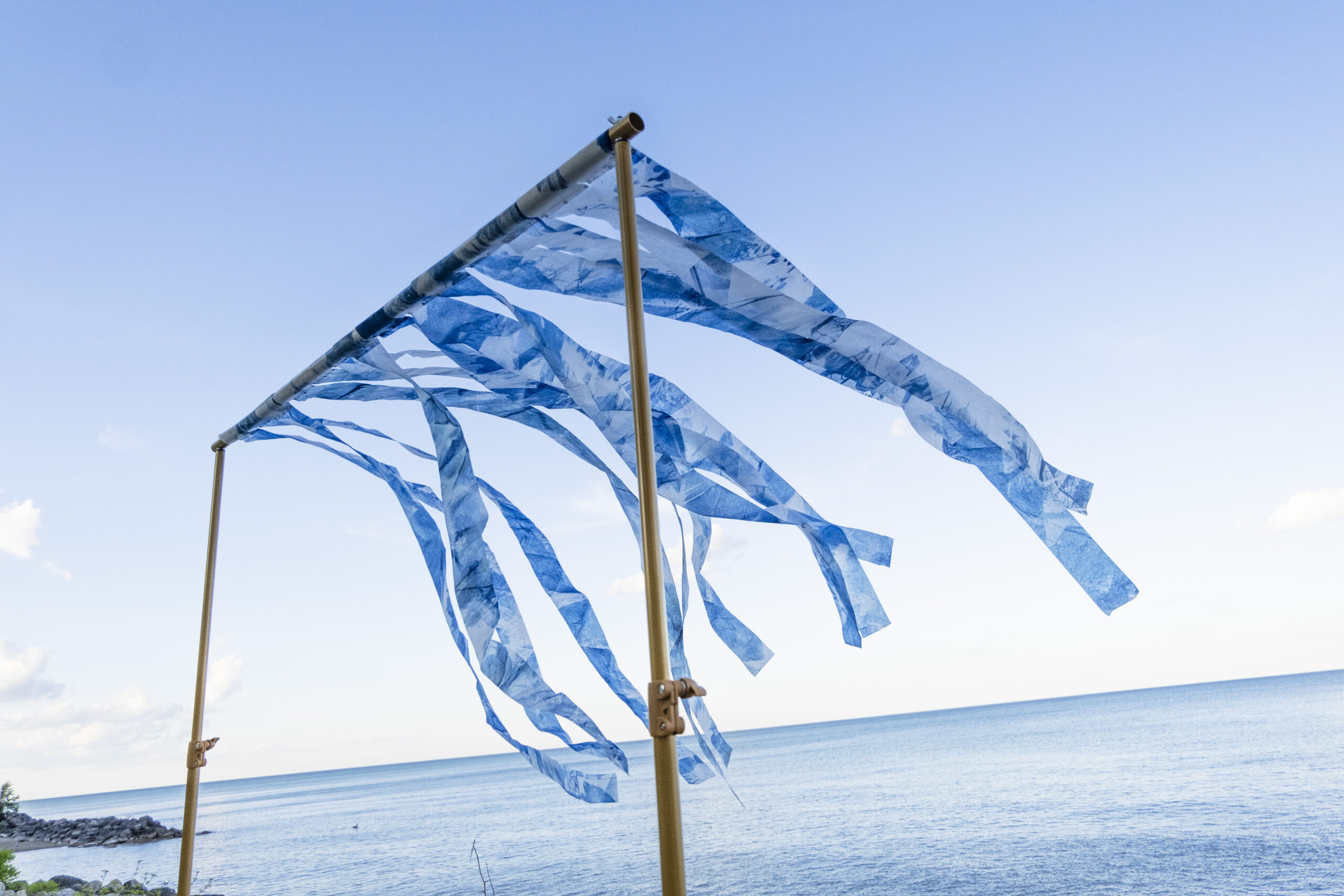 narrow cyanotype streamers floating in the breeze while attached to a golden photo stand