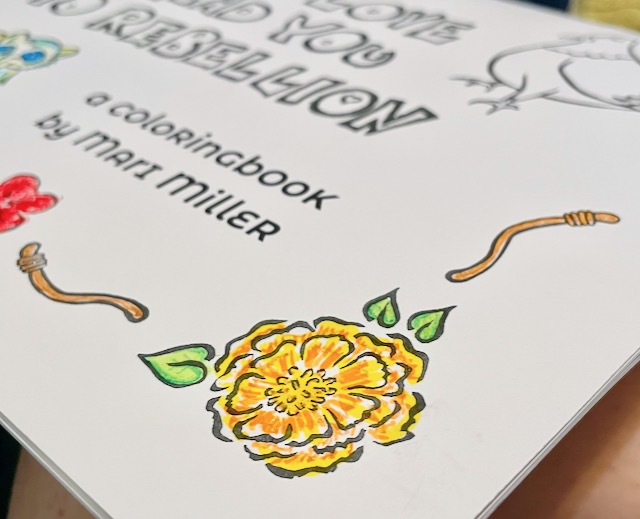 black and white cover of a coloring book that's been partially colored in, showing a marigold and two worms. Other partial figured fade into the background, along with text that says, "a coloringbook by Mari Miller"